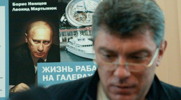 Opozīcijas politiķis Boriss Ņemcovs pozē savas un Leonīda Martiņuka sarakstītās grāmatas par prezidenta Putina privilēģijām "Verga dzīve galerās" vāka fona. Foto: ITAR-TASS/LETA