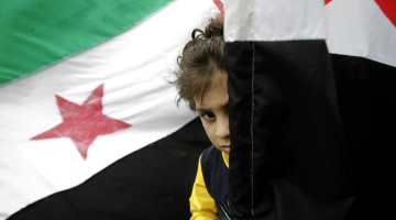 Bērns pie Sīrijas valsts karoga. Foto: AFP/LETA