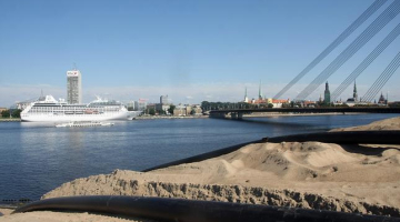 Kruīza kuģis piestātnē Daugavas labajā krastā un smilšu kalns pretējā krastā. Foto: Edijs Pālens, LETA