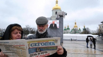 Cilvēki lasa par Ukrainas vēlēšanu rezultātiem. Foto: AFP/LETA