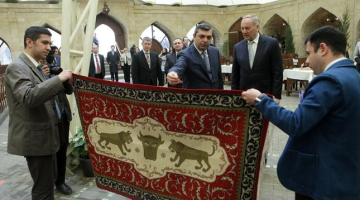 Baku vecpilsētas administrācijas vadītāja vietnieks Samirs Nurijevs (no kreisās) un Latvijas Valsts prezidents Andris Bērziņš šopavasar ekskursijas laikā Baku vecpilsētā apskata Azerbaidžānas meistaru darinātu paklāju. Foto: Ieva Čīka, LETA