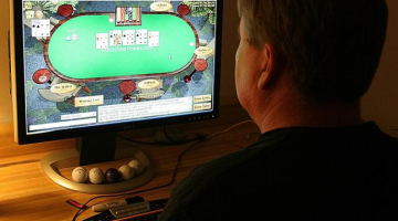 Vīrietis spēlē pokeru ar savu datoru. Foto: AFP/LETA