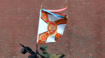 Krievijas armijas karavīrs uz bruņutransportiera nostiprina Svētā Georga karogu, gatavojoties 9.maija parādei Maskavas Sarkanajā laukumā. Foto: AFP/LETA