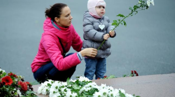 Sieviete ar bērnu noliek ziedus lielveikala jumta sabrukšanas upuriem. Foto: Evija Trifanova, LETA