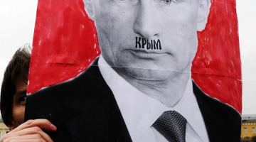 Plakāts ar Krievijas prezidenta Vladimira Putina portretu, kur sejā kā Hitlera ūsiņas ierakstīts Krievijas anektētās teritorijas - Krima - vārds. Foto: AFP/LETA