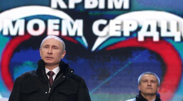 Vladimirs Putins (no kreisās) Krimas aneksijai veltītajā koncertā Sarkanajā laukumā Maskavā. Fonā - Krimas pašieceltais vadītājs Sergejs Aksenovs. Foto: ITAR-TASS/LETA