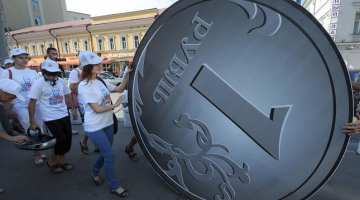 Krievijas prezidenta Putina politikas atbalstītāji pērnvasar sarīkoja akciju "Man tiešām patīk Putins", ripinot divus metrus lielu rubli, kura vērtība krītas. Foto: AFP/LETA