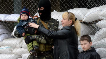 Lieldienu ģimenes foto Ukrainas promaskavas separātistu ieņemtajā Slavjanskā. Māte bērnus liek fotografēt kopā ar maskotiem separātistiem pie barikādēm. Foto: AFP/LETA