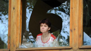 Sieviete Slovjanskā skatās caur sašautu logu. Foto: EPA/LETA