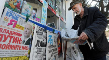 Krimā vīrs pie avīžu kioska lasa Krievijas laikrakstus. Foto: AFP/LETA