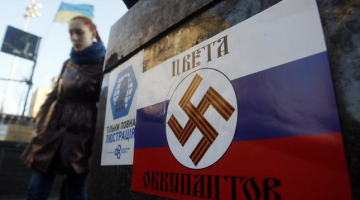 Kijevas Neatkarības laukumā pielīmēts plakāts, kas attēlo Krievijas karoga krāsas, uz kurām ir nacistu svastika. Uzraksts vēsta: okupantu krāsas. Foto: AFP/LETA