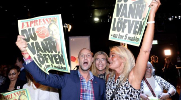 Zviedrijas sociāldemokrātu atbalstītāji līksmo par uzvaru vēlēšanās, rādot "dzeltenās" vakara avīzes "Expressen" vāku, kurā pausts atbalsts Stēfanam Levēnam. Foto: AFP/LETA