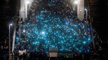 Protestētāji pret interneta nodokli Budapeštā uz Elizabetes tilta pār Donavu spīdina mobilo telefonu gaismiņas. Foto: EPA/LETA