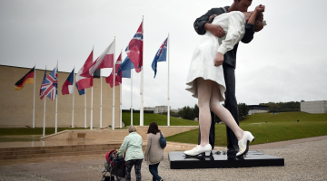 Šo monumentālo statuju Francijas pilsētā Kānā, Normandijā, izveidojis ASV mākslinieks Sevards Džonsons, iedvesmojoties no slavenā amerikāņu fotogrāfa Alfrēda Eizenšteda, kurš Ņujorkas Taimskvērā 1945.gada 14.augustā uzņēma foto, rādot, kā cilvēki priecājas, ka ir beidzies karš. Attēls uzņemts brīdī, kad amerikāņi uzzināja par Japānas kapitulāciju Otrajā pasaules karā. Foto: AFP/LETA