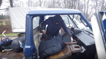 Nelegālie imigranti tiek izvilkti no slēptuves automašīnas grīdā. Foto: Valsts robežsardze/Delfi