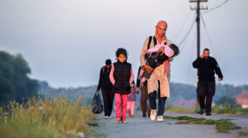 Ungārijas policists pavada bēgļus, kas apturēti pie Tisas upes netālu Segedas pilsētas, kas atrodas 170 km attālumā no galvaspilsētas Budapeštas. Foto: AFP/LETA