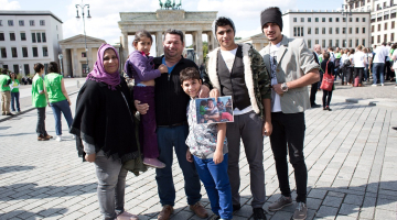 Sīriešu bēgļu ģimene Berlīnē pie Brandenburgas vārtiem pozē: no kreisās - Nada, Noor, Laith Majid Al-Amirij, Taha, Ahmeds un Mustafa. Foto: EPA/LETA