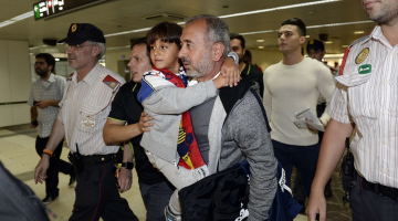 Sīrijas bēgli Osamu Abdulu Mohasenu al Ghadabu un viņa dēlu Zaidu Barselonas dzelzceļa stacijā sagaida Spānijas imigrācijas dienesta pārstāvji. Foto: AFP/LETA
