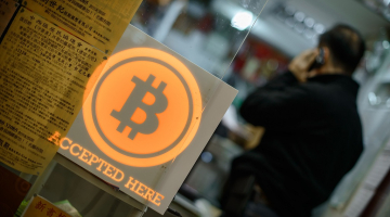 Virtuālā valūta "Bitcoin" - ar to var norēķināties te, rakstīts kādā Honkongas iestādē. Foto: AFP/LETA