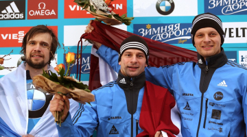 Uz pjedestāla Martins Dukurs (centrā), Tomass Dukurs un krievu sportists Aleksandrs Tretjakovs. Foto: EPA/LETA
