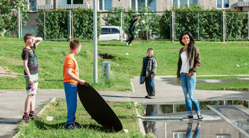 Bolderājas puikas ielenkuši Aminatu fotografēšanas laikā un pat palīdz izgaismot dziedātājas seju.