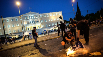 Protestētāji pie Grieķijas parlamenta ēkas Atēnās pagājušajā naktī, kad apsprieda reformu plānu. Foto: AFP/LETA