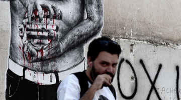 Attēlā redzamais grafiti Atēnās var izrādīties grieķiem atbilstošs - būs krietni jāsavelk jostas. Foto: AFP/LETA