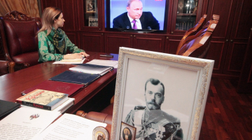 Kas ir prokurores galvā? Krimas ar pret Ukrainu vērstām apsūdzībām bēdīgi pazīstamā prokurore Natālija Poklonska decembrī TV vēro prezidenta Putina uzstāšanos, bet viņas darba kabinetā uz galda liels cara Nikolaja II portrets. Foto: ITAR-TASS/LETA