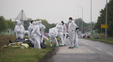 Brīvprātīgie aizsardzības tērpos savāc atkritumus, kas palikuši pēc migrantiem, kad tie šķērsoja Serbijas un Horvātijas robežu. Foto: EPA/LETA