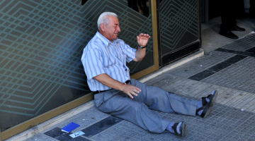 Grieķu pensionārs Giorgoss Hatzifotiadis sēž pie bankas un raud, uzzinājis, ka atļauts izņemt tikai 120 eiro no pensijas. Foto: AFP/LETA