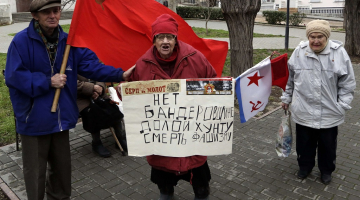 Nemainīgā pārliecība arī šodien Krievijas Ukrainai atņemtajā Sevastopolē - padomju laikus piedzīvojušie tur plakātu ar uzrakstu: "Nē baderoviešiem, nost ar huntu, nāvi fašismam!". Foto: AFP/LETA