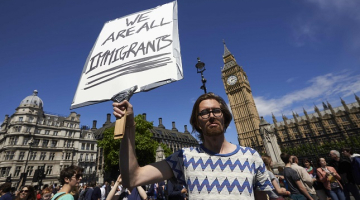 Protesta akcijā Londonā vīrietis tur plakātu ar uzrakstu: "Mēs visi esam imigranti." Foto: AFP/LETA