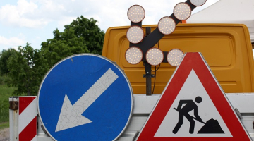 Satiksmi regulējošas ceļa zīmes uz ceļu būves automašīnas.