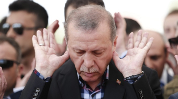 Turcijas prezidents Redžeps Tajips Erdogans lūdzas kapsētā pie militārā apvērsuma mēģinājuma laikā bojāgājušo zārkiem Stambulā. Foto: EPA/LETA