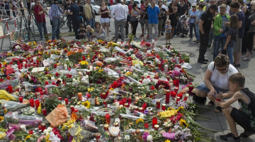 Cilvēki liek ziedus pie Minhenes tirdzniecības centra. Foto: AFP/LETA