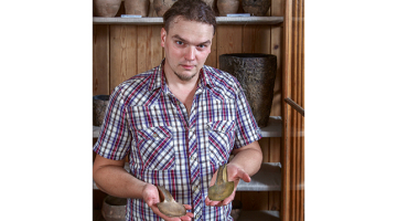 Artūrs Tomsons tur rokā divus bronzas cirvīšus, kuri zināmi kopš 19.gadsimta. Viens ir oriģināls bronzas laikmeta ierocis, otrs — 19. gadsimta pakaļdarinājums, ko var uzskatīt par vienu no pirmajiem eksperimentālās arheoloğijas paraugiem.