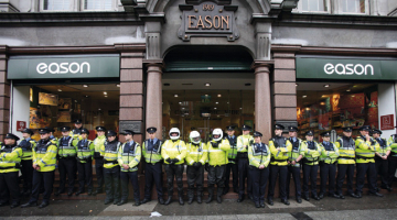 Policijas «mūris» pie grāmatnīcas Dublinā, kur 4.septembrī Tonijs Blērs ieradās uz prezentāciju un autogrāfu sniegšanu. Viņu sagaidīja aptuveni 200 protestētāji. Foto — AFP/LETA