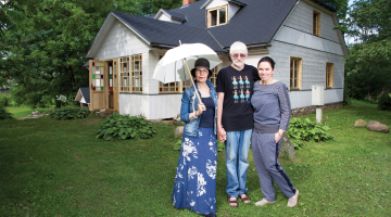 Ilze un Jānis Avotiņi ar meitu Kristīni Luīzi pie savām lauku mājām.