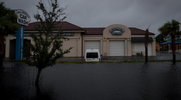 Plūdu ūdens ieskauj automašīnu mazgātavu Floridā, Bonita Springs.