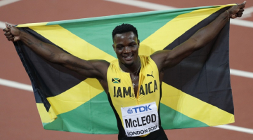Jamaikas skrējējs Omars Makleods svin uzvaru šovasar 110 m skrējienā. Viņam rokās Jamaikas karogs. Foto: AFP/LETA