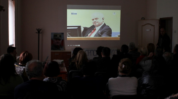 Ratko Mladiča (attēla centrā) dzimtajā Kalinovikā Bosnijā un Hercegovinā cilvēki televīzijā skatās tiesas sprieduma pasludināšanu. Foto: Reuters/LETA