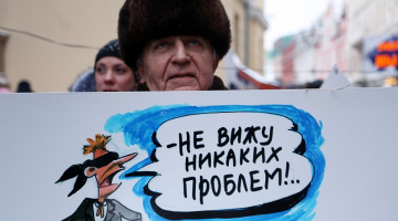 "Neredzu nekādu problēmu," vēsta uzraksts karikatūrā, kuru tur pret izglītību latviešu valodā noskaņots piketētājs pie Saeimas ēkas. Foto: Edijs Pālens, LETA