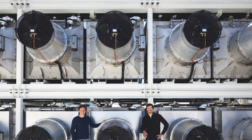 Climeworks līdzdibinātāji Kristofs Gebalds (pa kreisi) un Jans Vircbahers pie gaisa pārtveršanas rotoriem uz rūpnīcas jumta Hinvilas ciemā Šveicē.
Foto — The New York Times