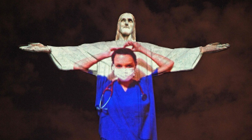 Slavenā Jēzus Kristus statuja Riodežaneiro Lieldienās tika izgaismota mediķa virsvalkā. Ārsti fotgrafējās uz tās fona. Foto: AFP/Scanpix/LETA