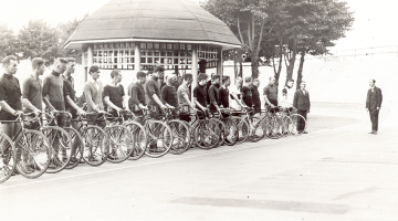 Sacensību atklāšanas parāde sporta biedrības Marss trekā pagājušā gadsimta 20. gados. Fonā — arhitekta Eižena Laubes projektētā lapene.
Foto no Latvijas Sporta vēstures muzeja fondiem