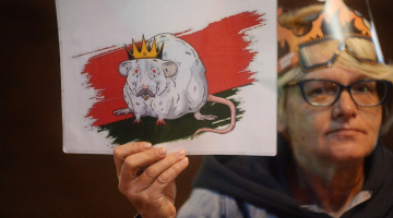 Protestētāja uzlikusi kroni galvā un rokā tur karikatūru, kurā Aleksandrs Lukašenko attēlots paša iemīļotajā žurkas tēlā, kā viņš apsaukā protestētajus. Foto: EPA/Scanpix