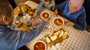 Ukrainiete Olha Habro ar dēlu un mazdēlu pusdienas sāk ar pašas gatavotu boršču.
Foto — The New York Times