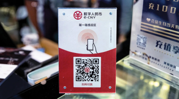 Cenu zīme kādā Ķīnas veikalā ar digitālās valūtas QR kodu