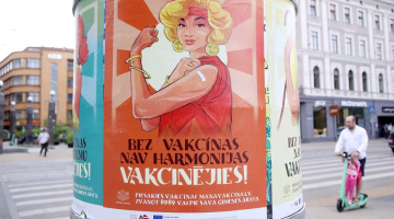 Vakcinācijas pret Covid-19 vides plakāti uz reklāmstaba. Foto: Paula Čurkste, LETA