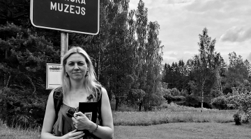 Rakstniece Inga Žolude autobusu pieturā, kas atrodas netālu no Vecās skolas, kurā mācījies Jānis Poruks. Skolā saglabāta autentiska mācību klasīte no viņa laika un rakstnieka dzīves un daiļrades izzināšanai atvēlēta  istabiņa.
Foto no Ingas Žoludes privātā arhīva